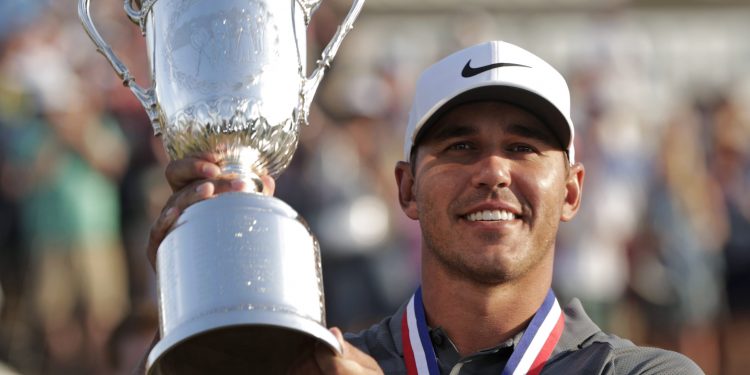 Brooks Koepka holds up the Golf Champion Trophy after winning the US Open Golf Championship, Sunday