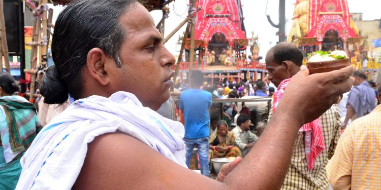 A devotee offers Rasagola to deities near their chariots in Puri, Wednesday. 