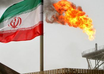 A gas flare on an oil production platform in the Soroush oil fields seen alongside an Iranian flag (AP)