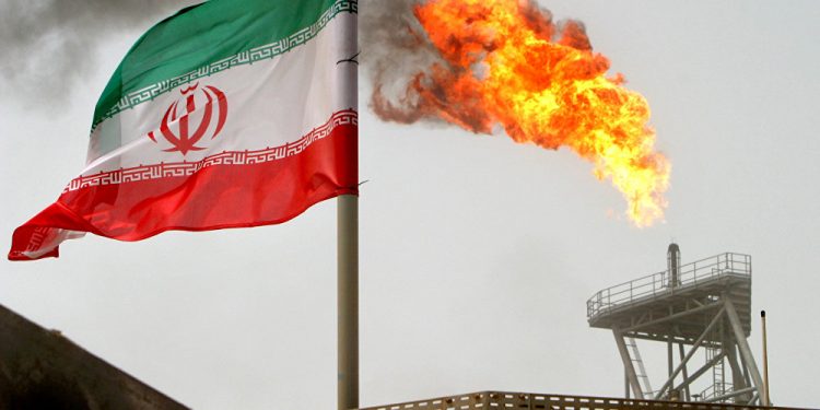 A gas flare on an oil production platform in the Soroush oil fields seen alongside an Iranian flag (AP)