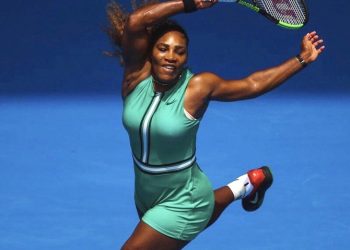 Serena Williams warmed up on Rod Laver Arena in a long, black raincoat which she discarded to reveal a figure-hugging, bottle green one-piece costume paired with fish-net compression stockings. (REUTERS)