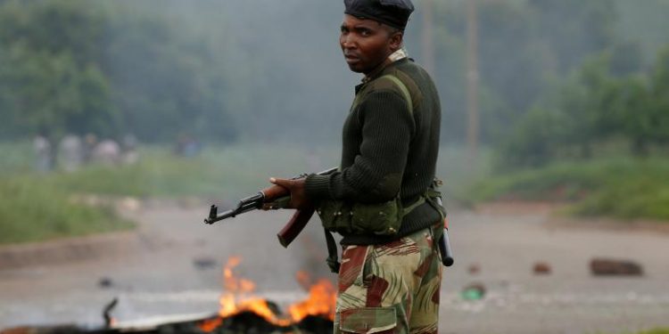 A soldier stands before a burning barricade during protests in Harare