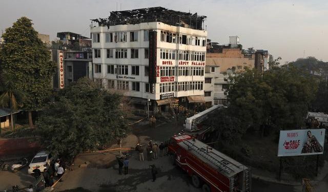 Onlookers stand on the rooftop of a building as they look at a hotel where a fire broke out in New Delhi, India, February 12, 2019. (REUTERS)