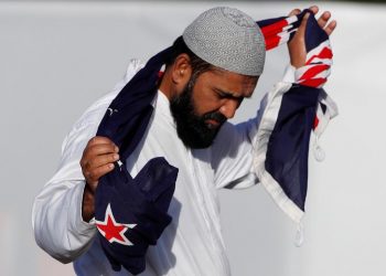 A man holding a New Zealand flag reacts during a burial ceremony for victims of the mosque attacks, at the Memorial Park Cemetery in Christchurch, New Zealand