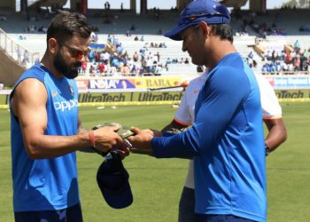 MS Dhoni hands over the camouflage military cap to Virat Kohli prior to the start of the third ODI against Australia at Ranchi, Friday