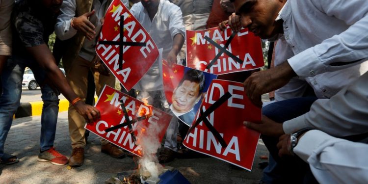 FILE PHOTO: Demonstrators burn Chinese goods and poster of Chinese President Xi Jinping during a protest organised by the activists of Swadeshi Jagran Manch, a wing of the Hindu nationalist organisation Rashtriya Swayamsevak Sangh (RSS), as they demand the boycott of Chinese products, in New Delhi, India, October 26, 2016. REUTERS/Adnan Abidi/File Photo