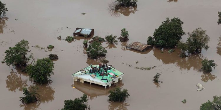 Groups of people stuck on rooftops with floodwaters up to window level in Beira. (AFP)