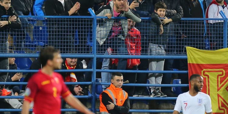 A home fan (C) makes an abusive comment to Raheem Sterling (R) during England’s match at Montenegro