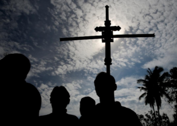 A man holds a cross during a mass burial of victims of the Easter Sunday bombings, at a cemetery in Sri Lanka, April 23