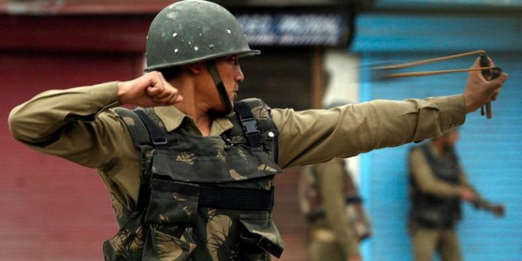 An Indian policeman uses a sling shot to tackle unruly protesters at Kashmiri protesters during an anti-election protest in Srinagar. (Reuters)