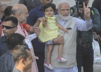 AHMEDABAD, APR 23 (UNI) Prime Minister Narendra Modi showing victory sign outside a polling station, after casting his vote for Lok Sabha election, in Ahmedabad on Tuesday. BJP National president Amit Shah and his granddaughter are also seen in the picture. UNI PHOTO-6U