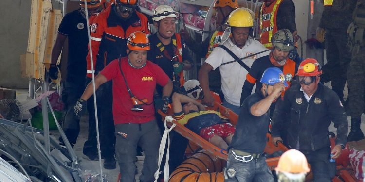 Rescuers carry an earthquake survivor after being pulled out from the rubble of a commercial building following Monday's 6.1 magnitude earthquake in Porac township, Pampanga province, north of Manila, Philippines, Tuesday, April 23, 2019. The strong earthquake struck the northern Philippines Monday trapping some people in a collapsed building, damaged an airport terminal and knocked out power in at least one province, officials said. (AP Photo/Bullit Marquez)