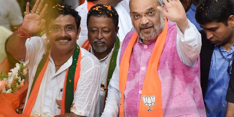 Kolkata: BJP National President Amit Shah waves at supporters during an election roadshow in support of north Kolkata's party candidate Rahul Sinha for the last phase of Lok Sabha polls, in Kolkata, Tuesday, May 14, 2019. Also seen is party leader Babul Supriyo. (PTI Photo/Ashok Bhaumik) (PTI5_14_2019_000126B)