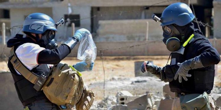 Investigators take samples from sand near a part of a missile that was suspected of carrying Investigators take samples from sand near a part of a missile that was suspected of carrying chemical agents