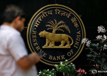 FILE PHOTO: A man checks his phone outside the Reserve Bank of India (RBI) headquarters in Mumbai, India April 5, 2018. REUTERS/Francis Mascarenhas/File Photo - RC1C6E0B3400