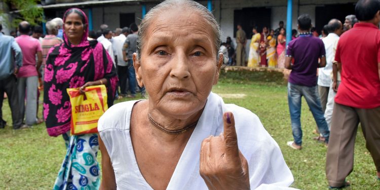 An elderly woman shows off her inked finger after casting her vote in the Rangapara Assembly constituency in Assam