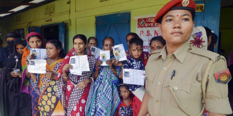 Women voters display their ID cards at a polling booth in Assam