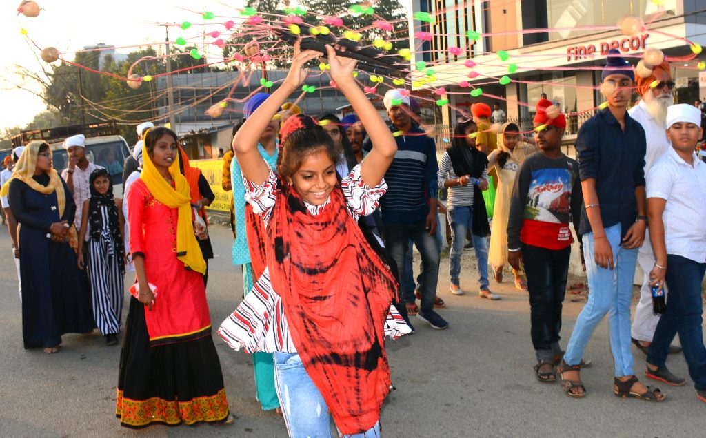 A girl swirling a decorative wheel during a procession for celebration of Guru Nanak Dev’s 550th birth anniversary in Sambalpur