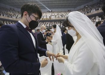 A couple wearing face masks exchanges their rings in a mass wedding ceremony at the Gapyeong in South Korea