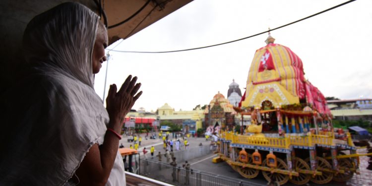 An elderly woman offers prayers to Lord Jagannath from a distance near Srimandir