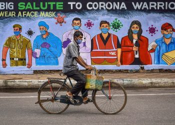 A cyclist rides past a mural paying salute to the frontline corona warriors in Vijayawada, Andhra Pradesh, India. (Image Credit: AFP)