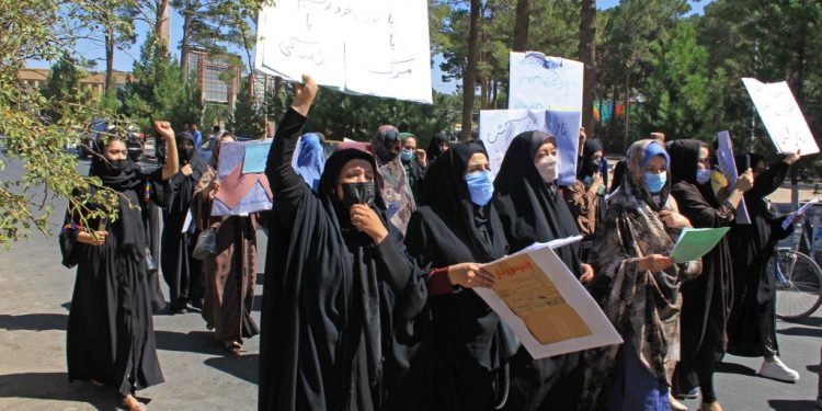 Afghan women hold placards and don burkas as they take part in a protest in Herat on September 2, 2021. (AFP)