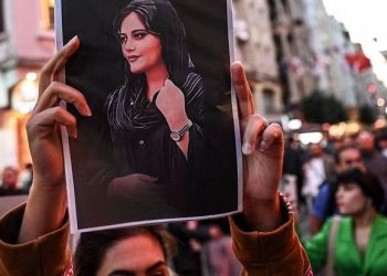 A protester holds up a portrait of Mahsa Amini. (Source: Wikimedia Commons)