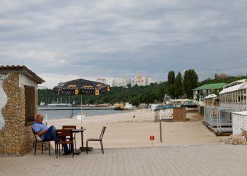 FILE PHOTO: A man sits beside a closed off beach in Odesa, Ukraine, June 6, 2022. REUTERS/Edgar Su/File Photo