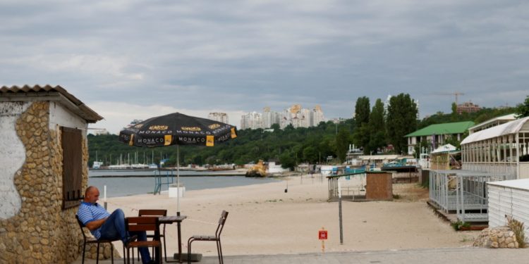 FILE PHOTO: A man sits beside a closed off beach in Odesa, Ukraine, June 6, 2022. REUTERS/Edgar Su/File Photo