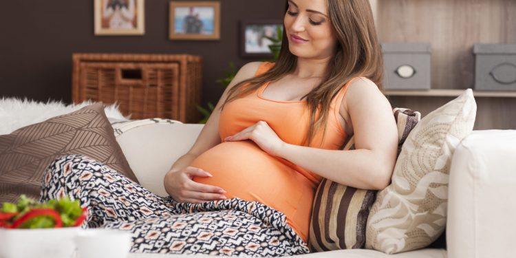 Beautiful natural woman in pregnant relaxing on sofa